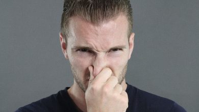 A man stopping his nose from smelling bad house smells