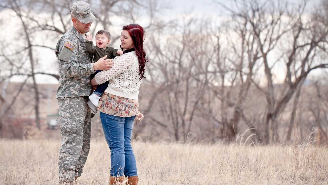 Military family hugging in field